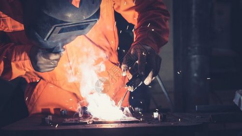 金属焊工与电弧接机一起工作在厂焊接钢材同时佩戴安全设备图片素材
